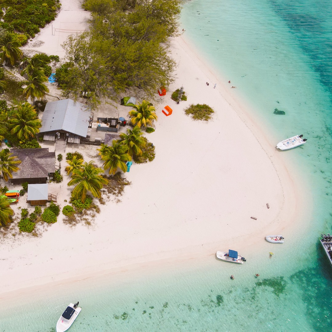 Indigo-House_exuma-chat-n-chill Aerial view of a beachfront restaurant on Stocking Island, surrounded by white sand and anchored boats.