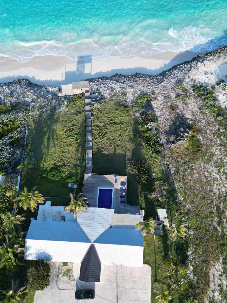 Direct overhead view of Indigo House Exuma, showing the villa, pool, boardwalk, and cliffside location above the ocean.
