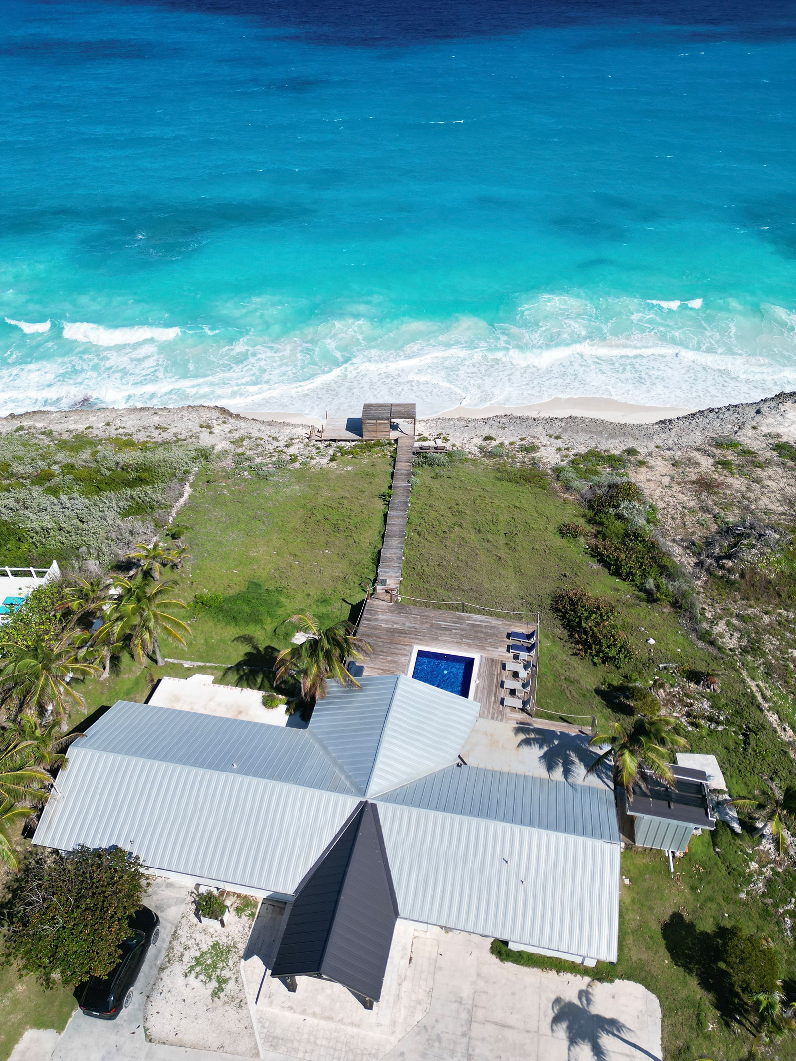 Indigo-House_grounds-2_1600 Aerial view of Indigo House in Exuma, showcasing amenities like the private pool and direct access to the turquoise ocean.