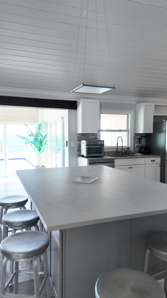 Well-lit kitchen island at Indigo House Exuma with bar seating and a window view.