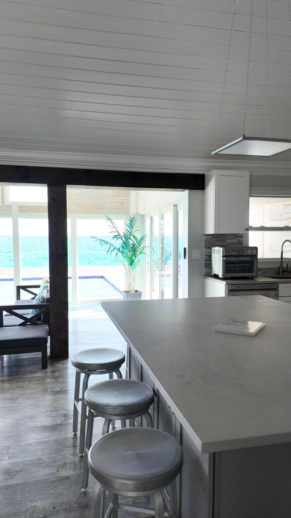 Kitchen island and dining space at Indigo House Exuma with ocean-facing windows and barstools.
