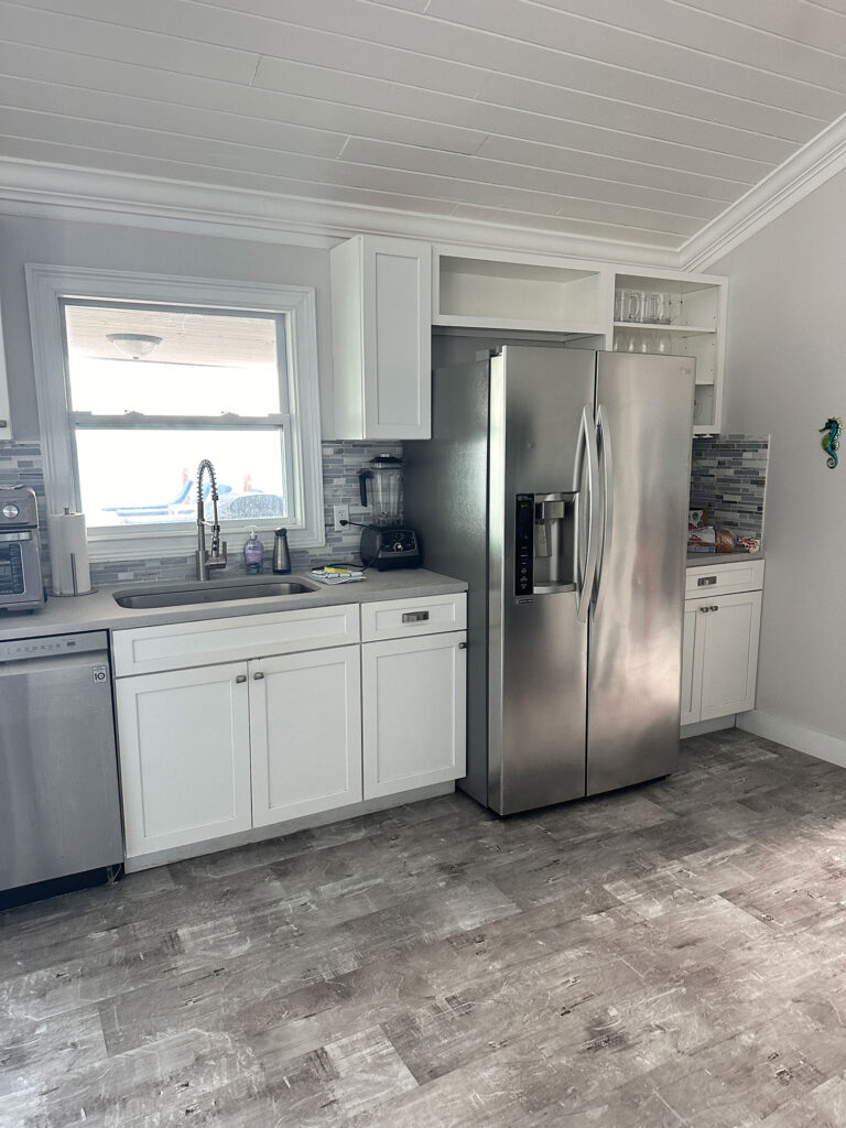 White kitchen at Indigo House Exuma with stainless steel fridge, tiled backsplash, and coastal-inspired finishes.