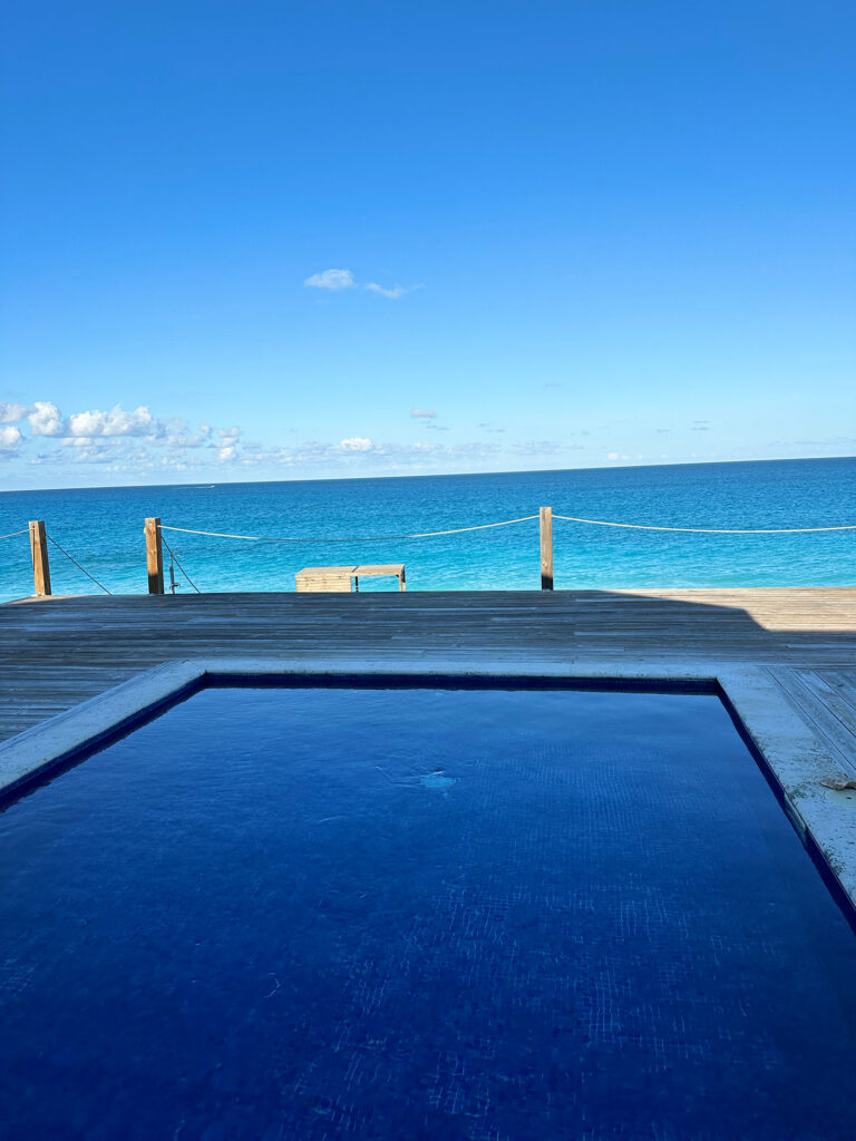 Heated pool at Indigo House Exuma with panoramic ocean views and a rope railing along the deck.